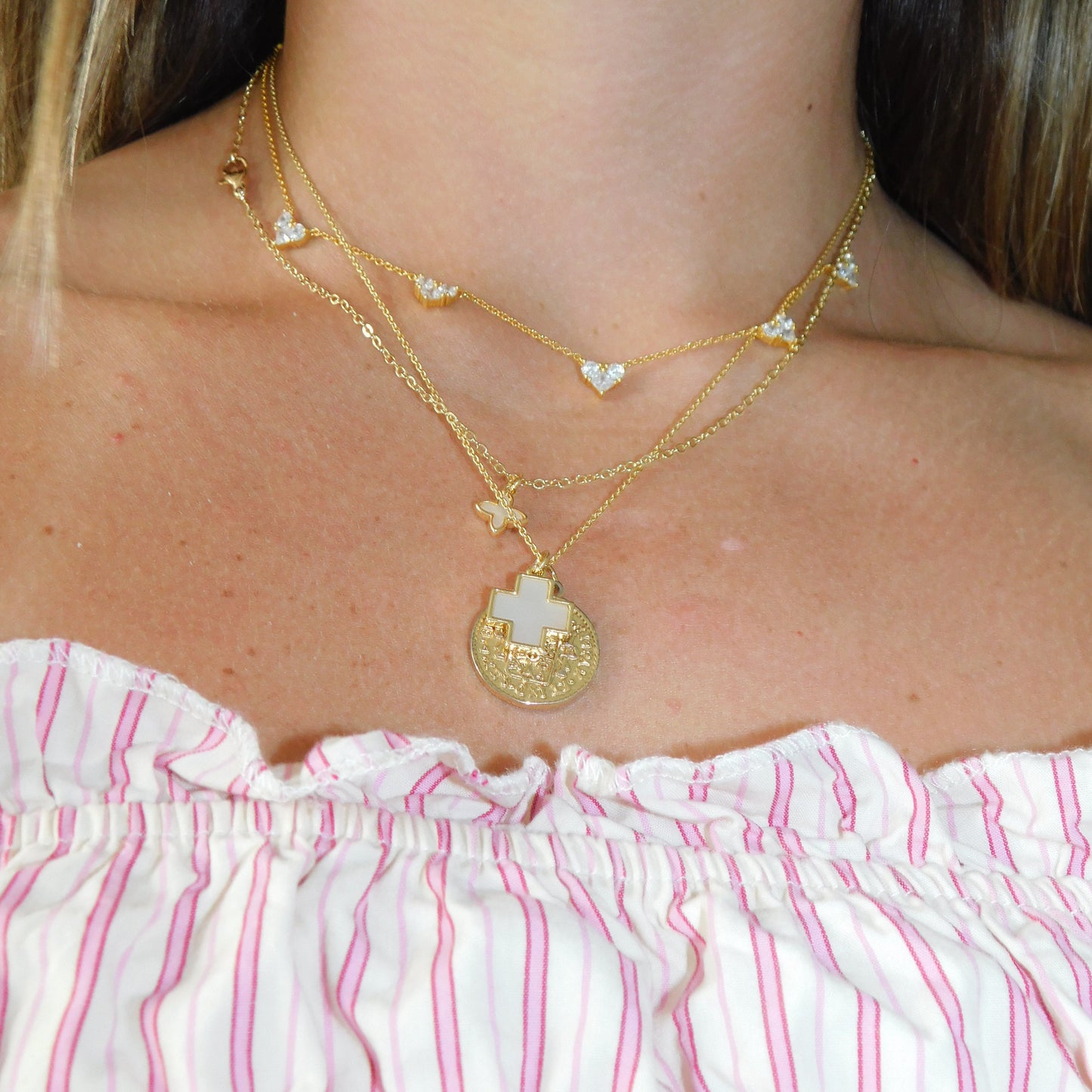 Close-up of a person wearing gold necklaces with a pink and white striped garment.
